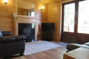 a living room with a fireplace and a television at Cul Darach Lodge, Glen Roy Nature Reserve in Roybridge