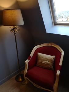 a red chair next to a lamp and a window at Villa Augeval Hôtel de charme & Spa in Deauville