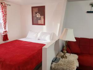 a bedroom with a bed and a red couch at Motel LA RÉFÉRENCE in Trois-Rivières
