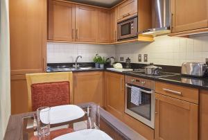 倫敦的住宿－Marlin Apartments London City - Queen Street，厨房配有木制橱柜和桌椅
