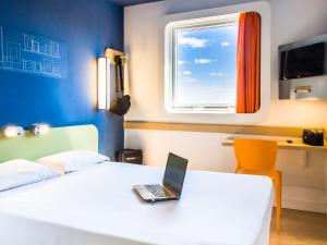 a bedroom with a laptop on a bed with a window at ibis budget Sertaozinho in Sertãozinho