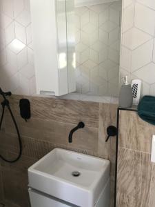 La salle de bains est pourvue d'un lavabo blanc et d'un miroir. dans l'établissement Trinity, à Balatonalmádi