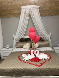 een bed met een hart van ballonnen en een taart bij Dimora Vittoria in Bari