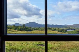 una ventana con vistas a un campo y a las montañas en Dunvegan Castle The Farmhouse Cottage, en Dunvegan