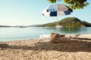 una silla y una sombrilla en una playa en Avra Beach Hotel en Nydri