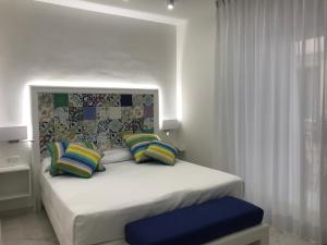 a bedroom with a white bed with colorful pillows at Amalfi Suite Boutique Hotel in Amalfi