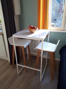 a white table and chairs with a bowl of fruit on it at Le Coquet in Saint-Omer