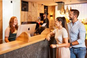 three people standing at a counter in a coffee shop at Der Postwirt in Söll +37 photos
