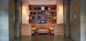 uma sala com uma biblioteca com cadeiras e uma mesa em The Fitzwilliam Hotel em Dublin