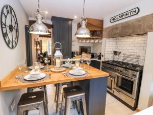 a kitchen with a wooden counter with stools in it at 1 Oakleys in Holmfirth