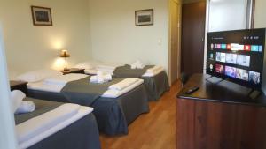 a room with four beds and a flat screen tv at Motell Svinesundparken in Halden