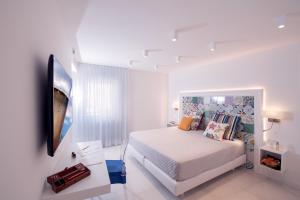 a white bedroom with a bed and a tv at Amalfi Suite Boutique Hotel in Amalfi