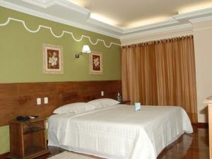 um quarto com uma grande cama branca num quarto em Hotel Dom Otto em Vespasiano