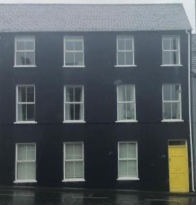 a black building with a yellow door on it at Queen Street Apartments in Enniskillen