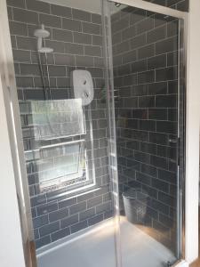a bathroom with a shower with black tiles at Kingfisher cottage in Worthing +29 photos