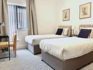 a bedroom with two beds and a table and a chair at Premium Apartments Thatcham Broadway in Thatcham