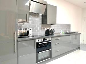 a kitchen with stainless steel appliances and white tiles at Premium Apartments Thatcham Broadway in Thatcham