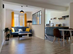 uma sala de estar com um sofá azul e uma mesa em Appartements Voltaire - Carcassonne Centre em Carcassonne