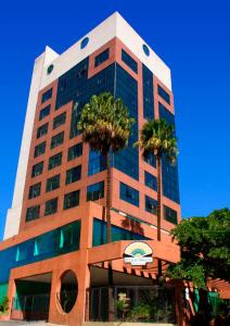 a tall building with palm trees in front of it at Leques Brasil Hotel Escola in São Paulo