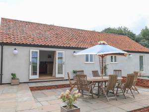 une table et des chaises avec un parasol sur une terrasse dans l'établissement Waveney View Cottage, à Great Yarmouth
