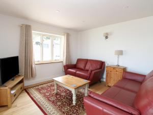 ein Wohnzimmer mit einem roten Sofa und einem Tisch in der Unterkunft Waveney View Cottage in Great Yarmouth