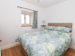 ein Schlafzimmer mit einem Bett mit blauer Decke und einem Fenster in der Unterkunft Waveney View Cottage in Great Yarmouth