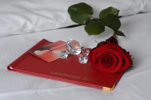 un libro rojo con una rosa roja en una cama en Landhotel Zerlaut, en Kisslegg