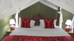 uma cama com almofadas vermelhas e brancas e 2 candeeiros em Osero Lodge em Ololaimutiek