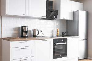 a kitchen with white cabinets and a stove top oven at Dziesiąte Piętro in Poznań