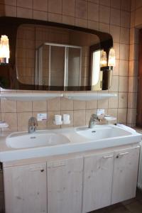 un bagno con due lavandini e un grande specchio di Haus Gassner a Bad Hofgastein