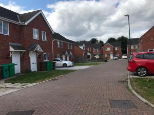 un coche rojo estacionado en una calle de ladrillo con casas en WHOLE HOUSE 3bedroom New Build 36 Nottingham en Nottingham