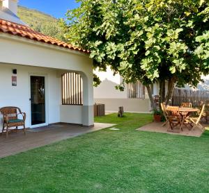 a backyard with a table and chairs and a tree at Casas de Alpedrinha in Alpedrinha