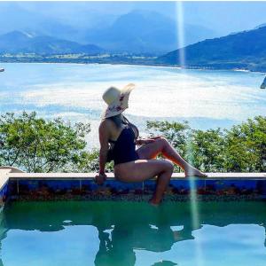una mujer sentada en el borde de una piscina en Chalé da Clarissinha en Mangaratiba