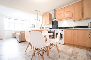 una cocina con armarios de madera, mesa y sillas en AAA Stay Garden Apartment, en Thatcham