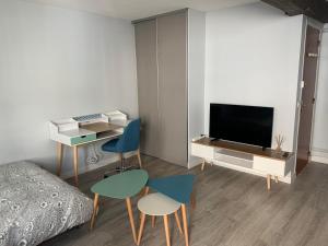 a bedroom with a bed and a tv and chairs at L'annexe in Compiègne