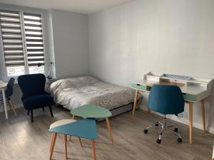 a bedroom with a bed and a desk and chairs at L'annexe in Compiègne