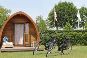 a small wooden cabin with two bikes parked in the grass at Buitengewoon Overnachten in Terheijden