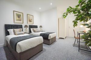 a bedroom with two beds and a table and a plant at Premium 2 Bed Apartments - Thatcham Broadway in Thatcham