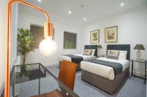 a hotel room with two beds and a glass table at Premium Apartments Thatcham Broadway in Thatcham