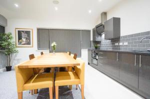 a kitchen with a wooden table and chairs in it at Premium Apartments Thatcham Broadway in Thatcham +8 photos