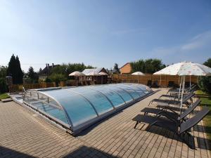 a swimming pool with chairs and an umbrella at Krisztián Apartmanház in Vonyarcvashegy