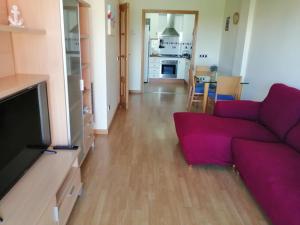 a living room with a purple couch and a kitchen at Apartamento playa Cambrils edificio Torresol in Cambrils