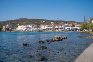 a beach with rocks in the water with houses at Studios Maniati in Elafonisos