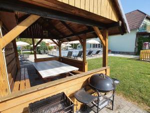 a wooden pavilion with a grill and a table at Krisztián Apartmanház in Vonyarcvashegy