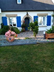 a house with blue doors and flowers in a yard at maison aux volets bleus in Quévert