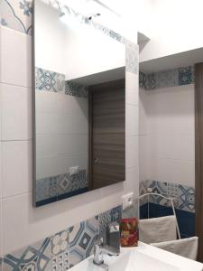 ein Bad mit einem Waschbecken und einem Spiegel in der Unterkunft Parsifal family room in Campofelice di Roccella
