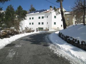 a snow covered road in front of a white house at Casa do Serrinho in Seia
