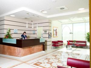 モシャーノ・サンタンジェロにあるBreaking Business Hotelの病院ロビーのカウンターに立つ女