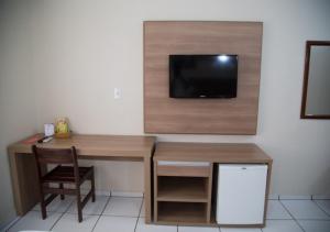 a room with a desk and a tv on a wall at Hotel Dona Beja in Araxá