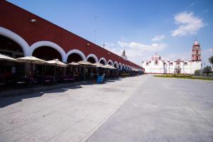 een groot rood-wit gebouw met tafels en parasols bij Hotel Santa Rosa by Rotamundos in Cholula